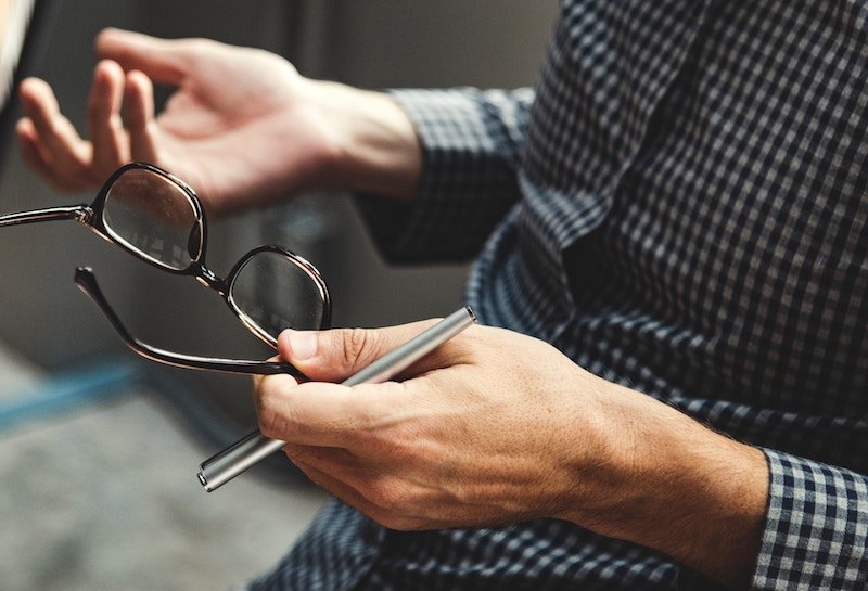 man holding his glasses and having a discussion